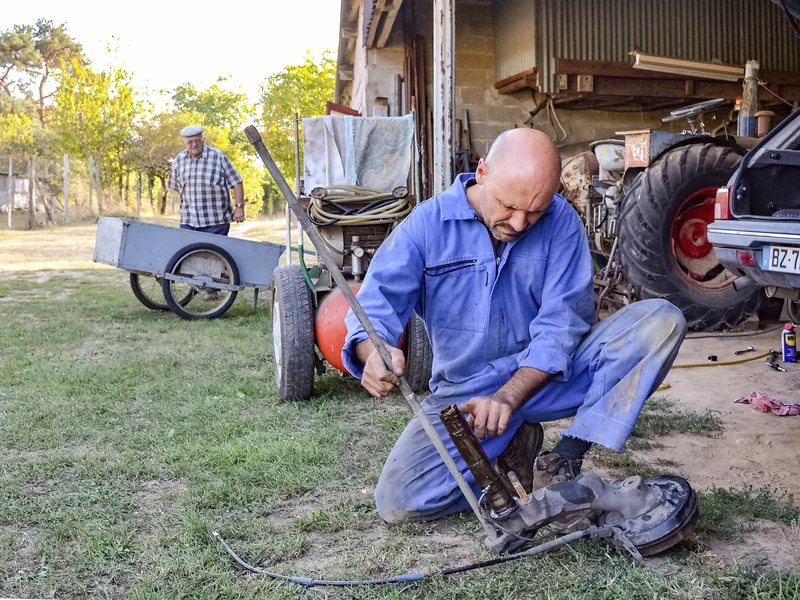 Agricultural mechanic maintaining working farm machinery